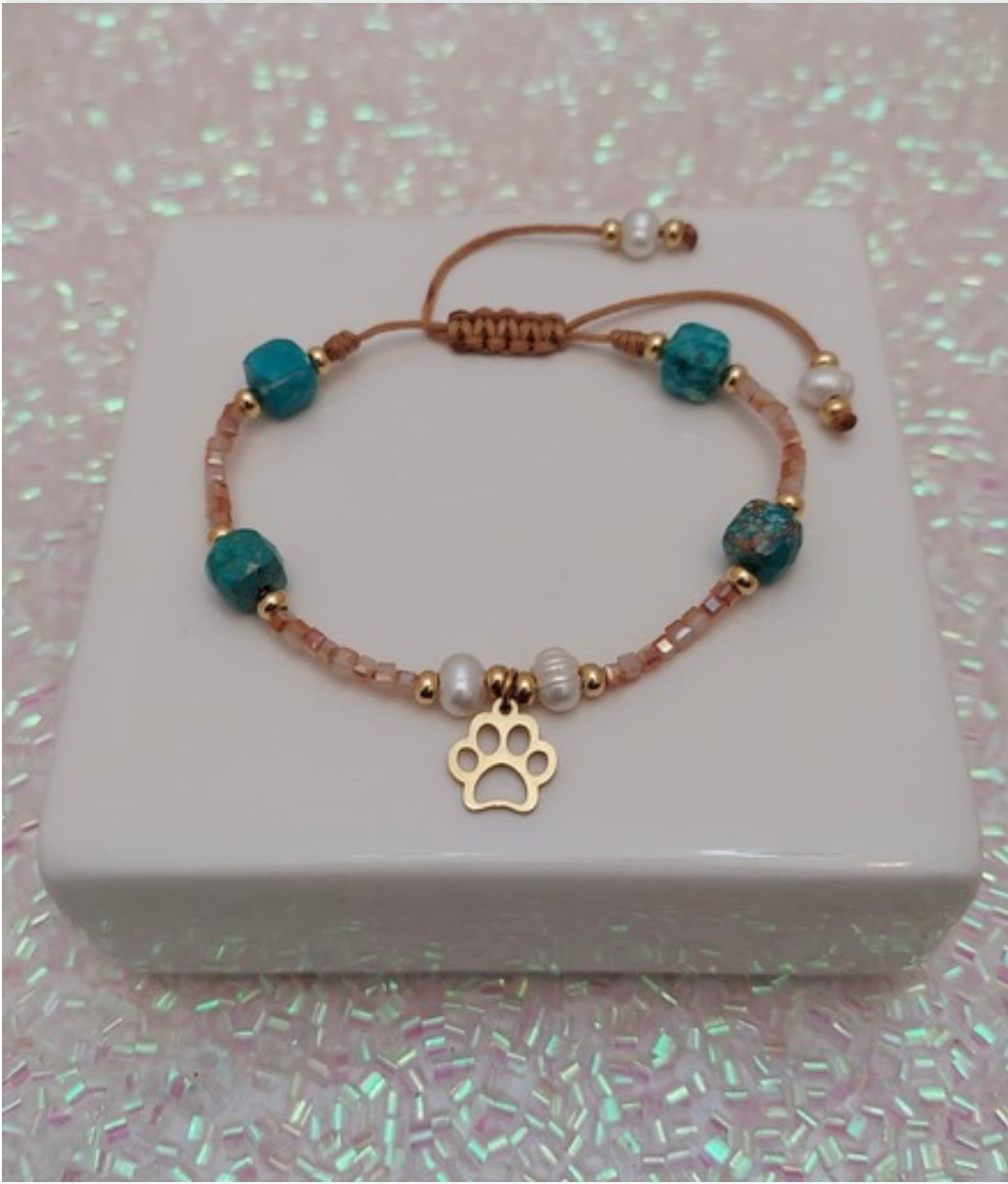 Pulsera en hilo con cuentas, perlas blancas y un charm de huellita